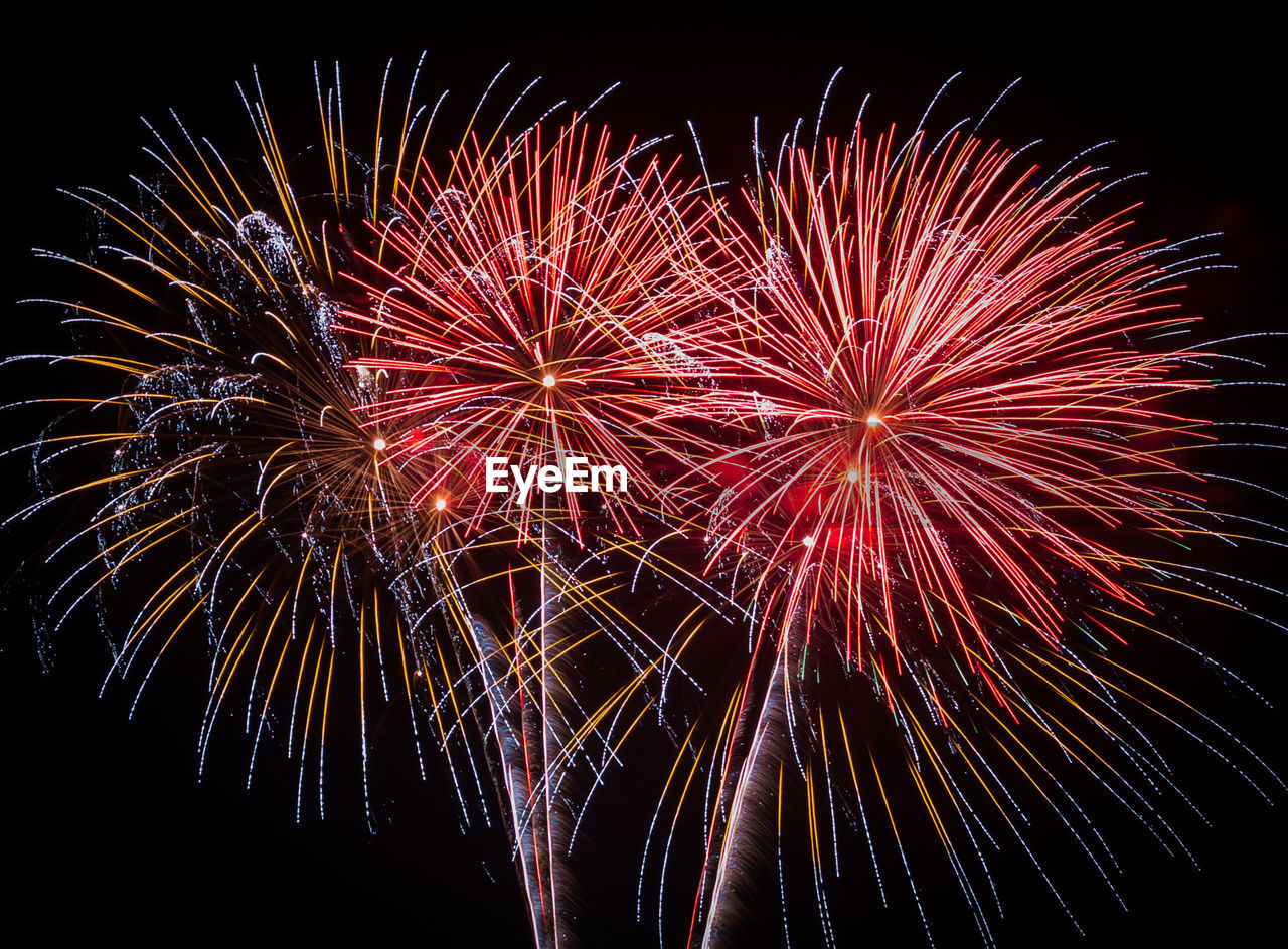 Close-up and low angle view of firework display at night
