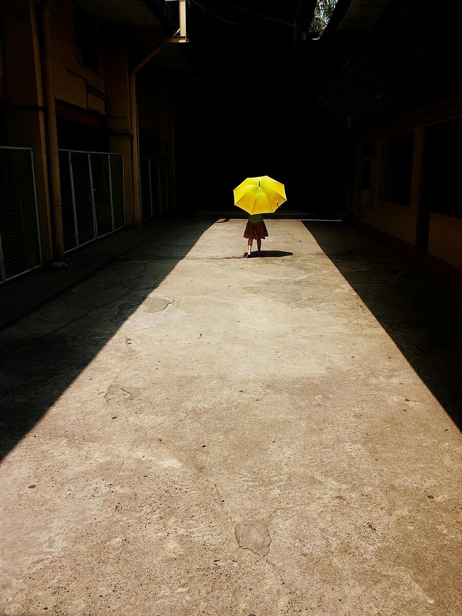 Lone person walking with yellow umbrella