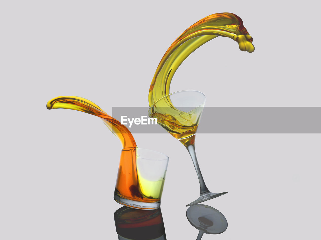 Close-up of drink spilling from glasses against white background