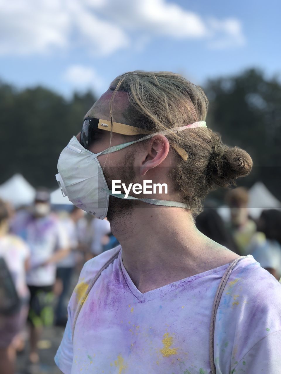 Young man wearing sunglasses and mask standing at music festival