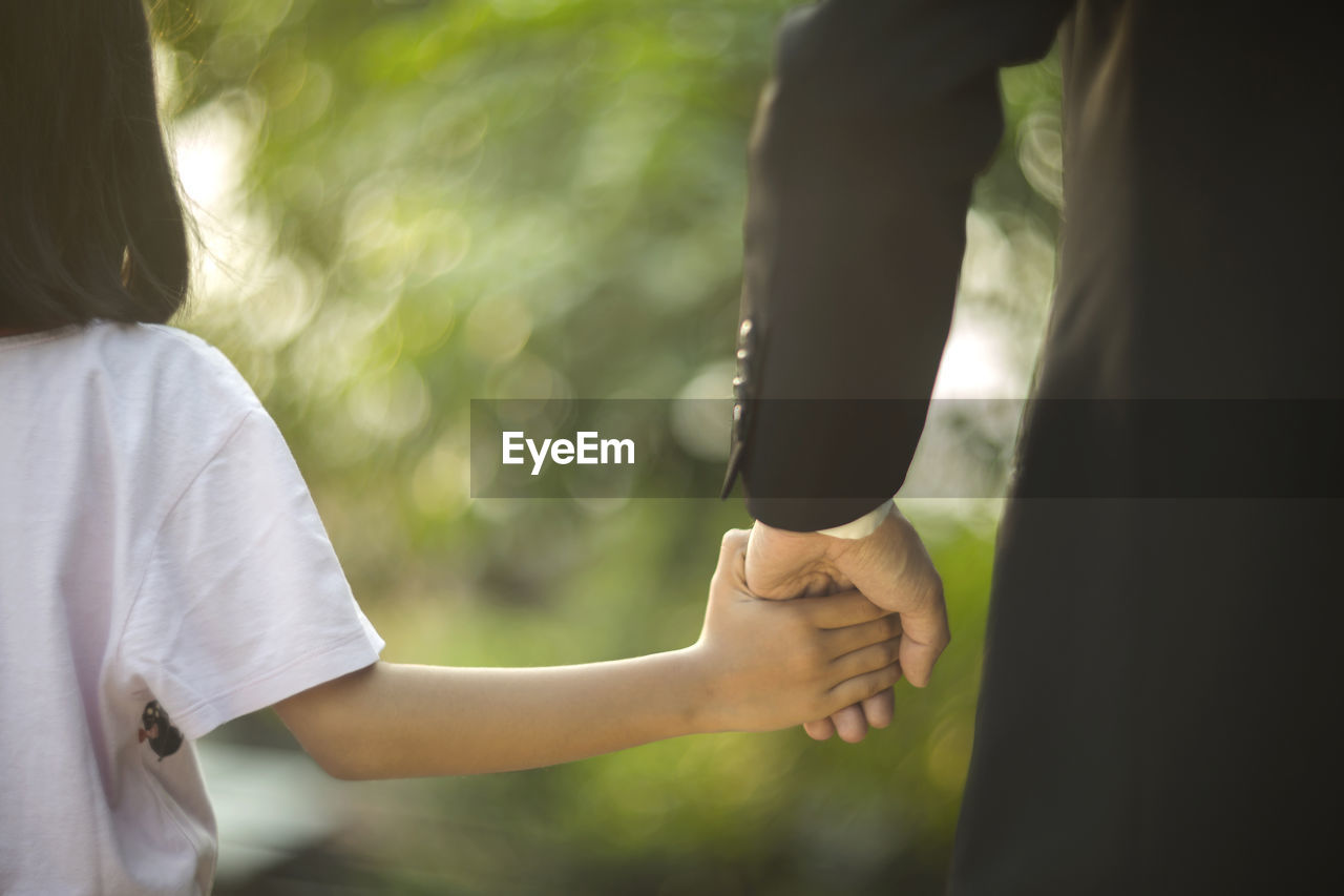 Cropped image of father and daughter holding hands