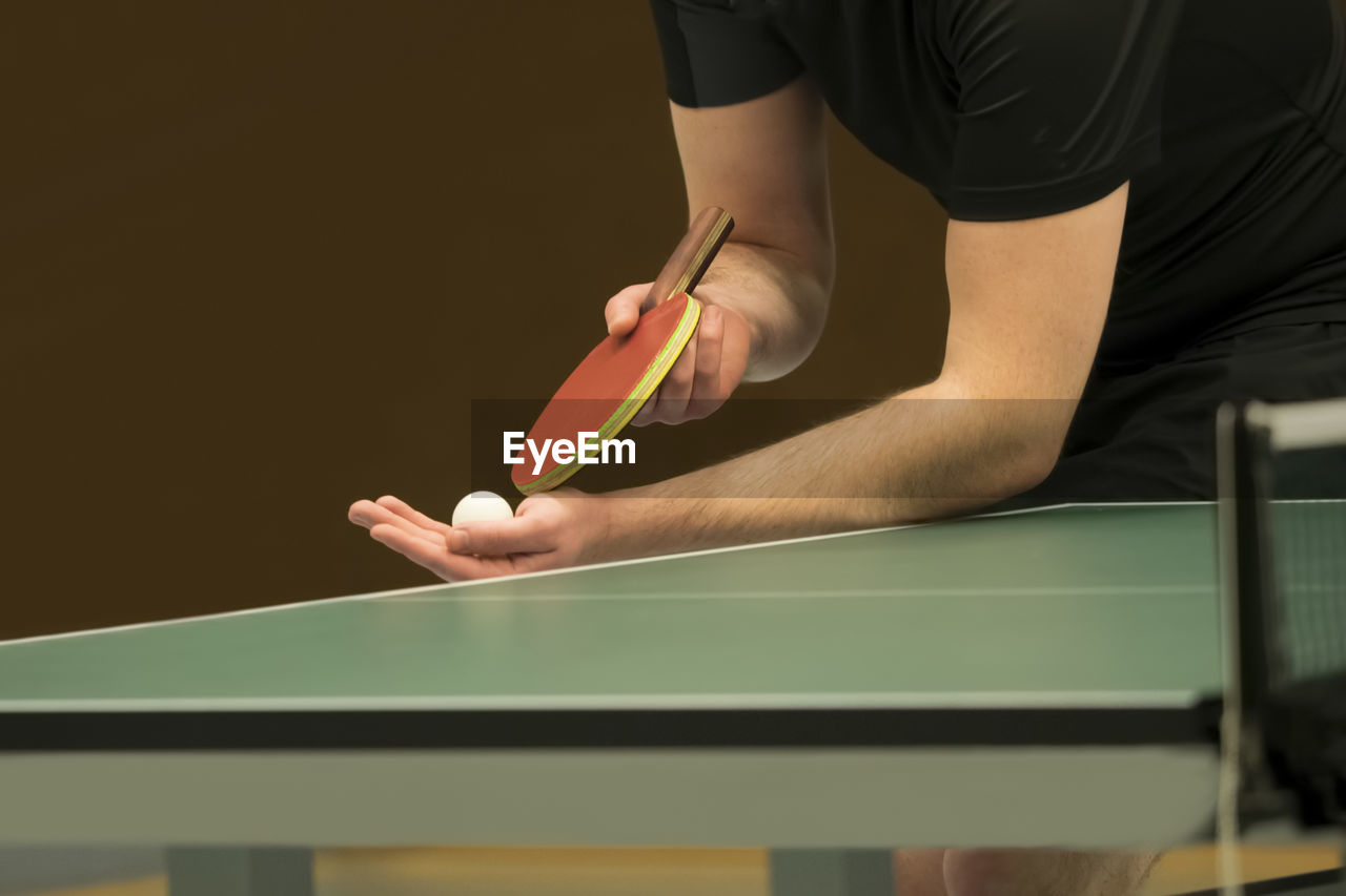 Midsection of man serving while playing table tennis