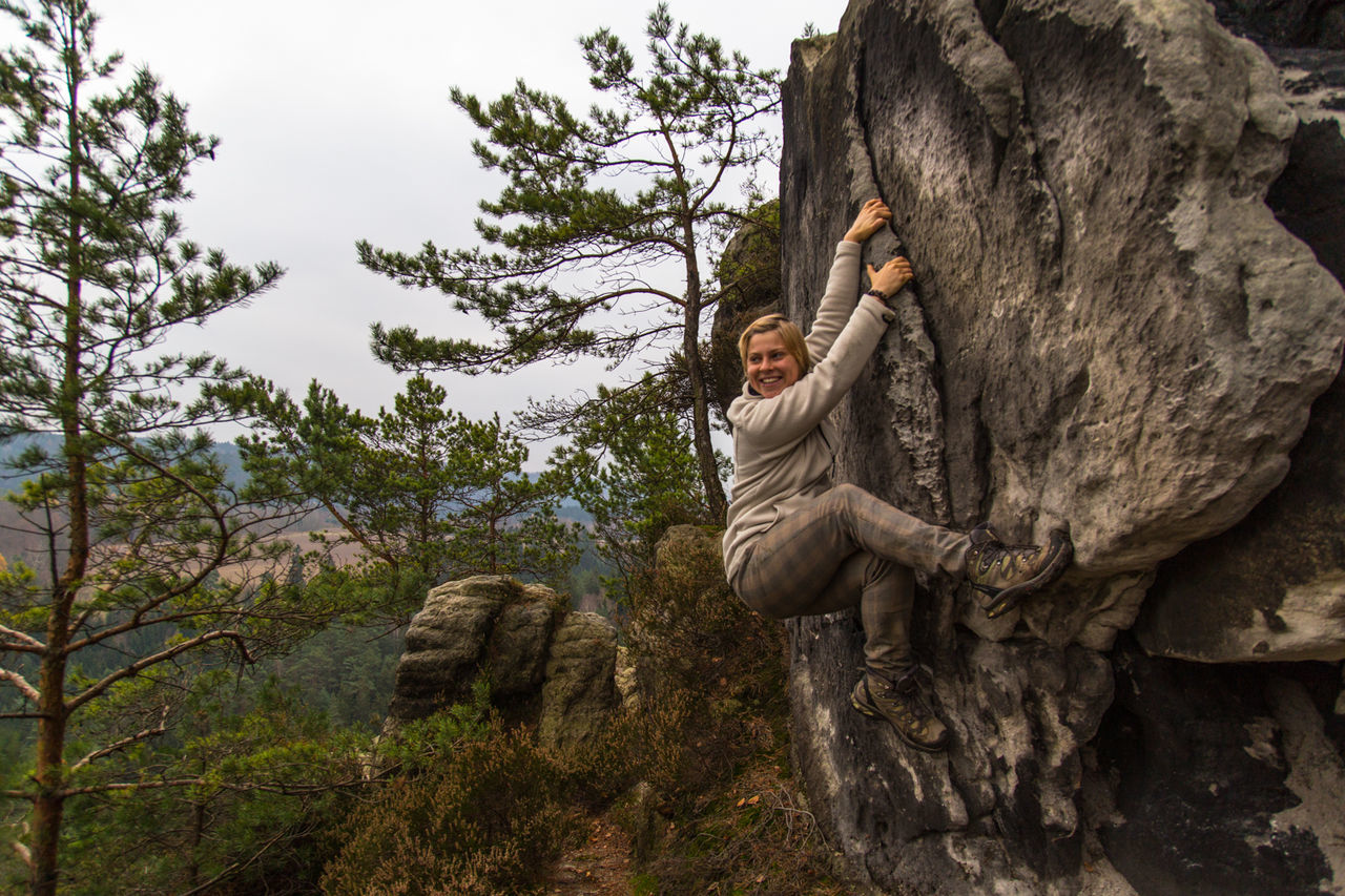 Smiling woman climbing rock on mountain