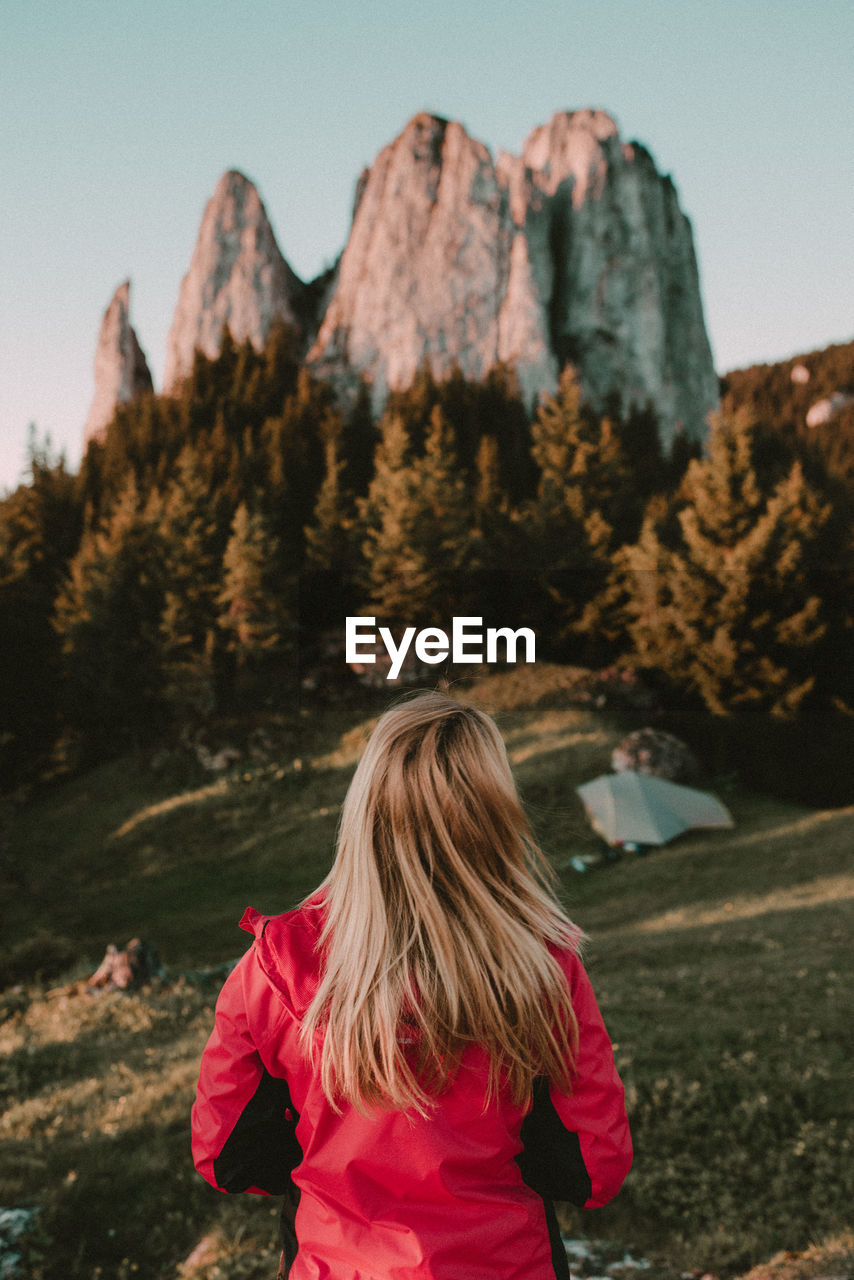 Rear view of woman looking at  mountain against clear sky