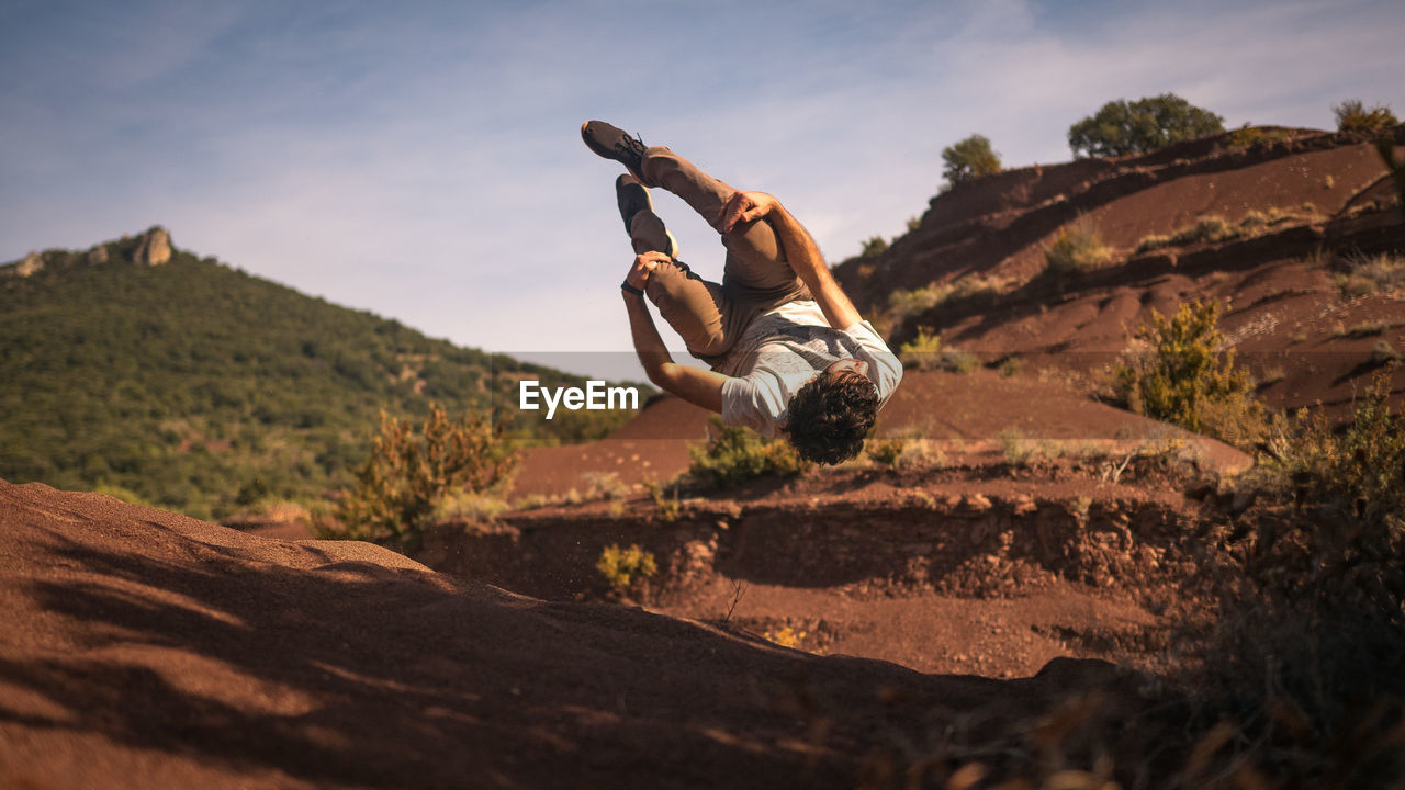 Low angle view of man practicing stunt against rock formations