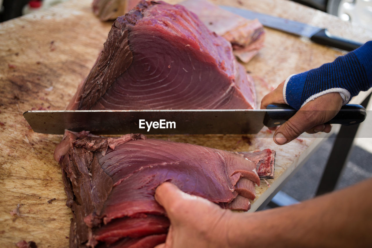 Cropped image of butcher cutting tuna