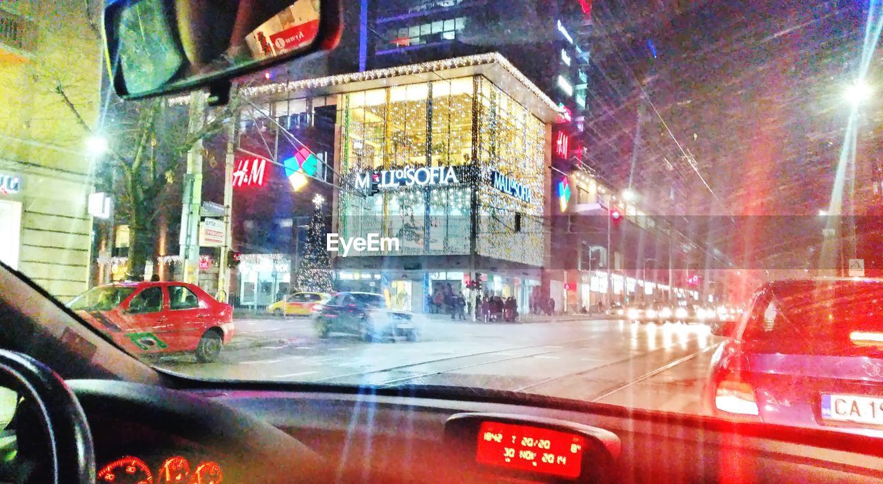 Illuminated buildings in city seen through car
