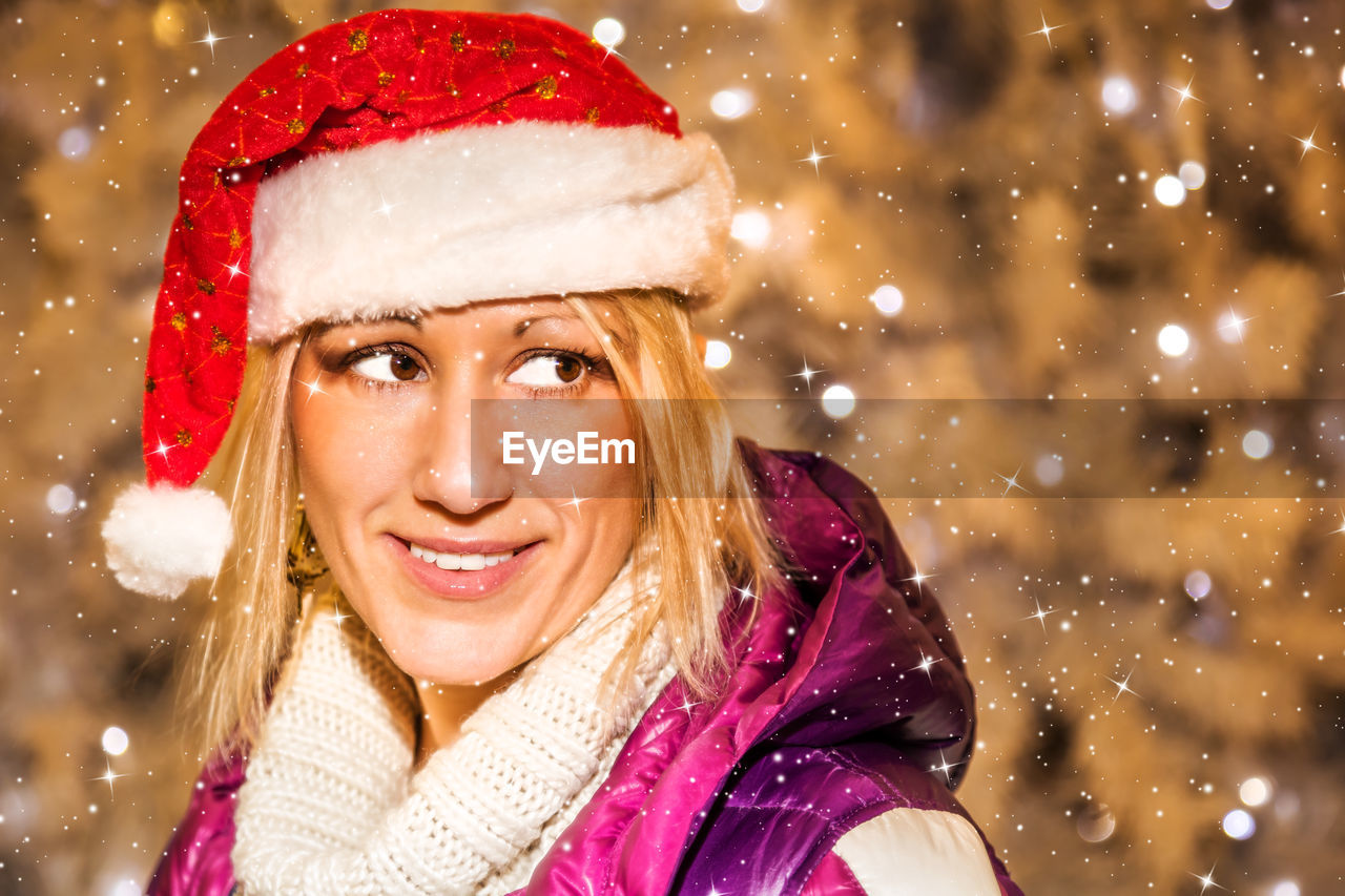 Close-up of smiling mature woman wearing santa hat during christmas