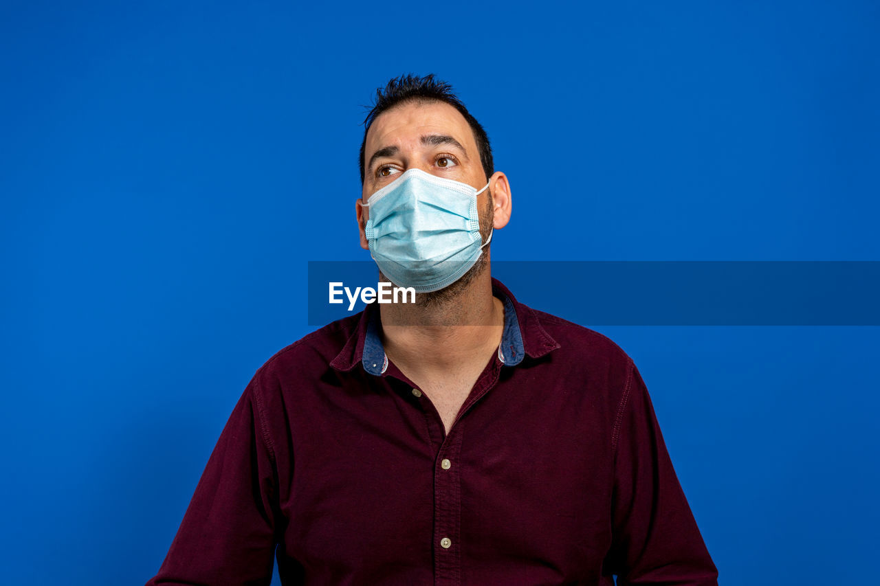 blue, portrait, one person, adult, studio shot, healthcare and medicine, colored background, surgical mask, front view, human face, looking at camera, blue background, men, clothing, indoors, person, occupation, surgeon, young adult, protective mask - workwear, glasses, doctor, copy space