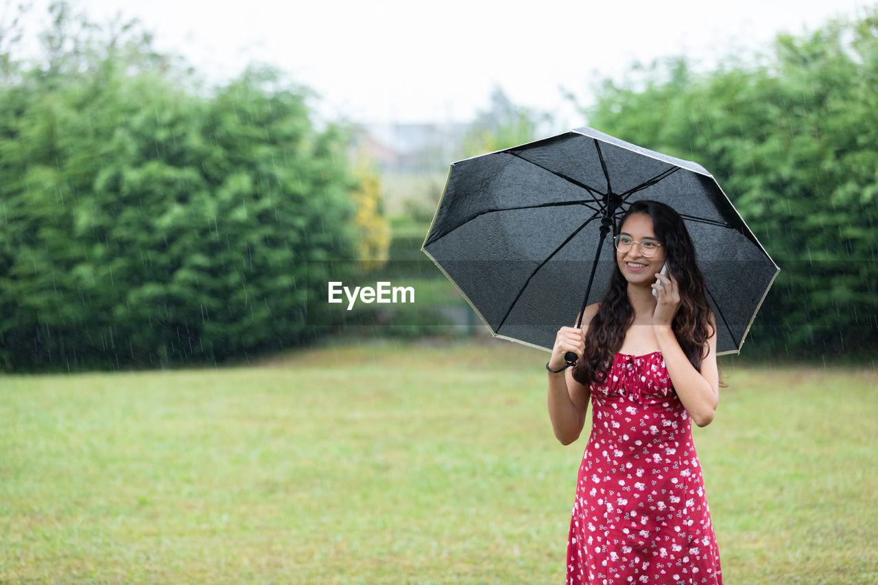 rear view of woman with umbrella standing against trees