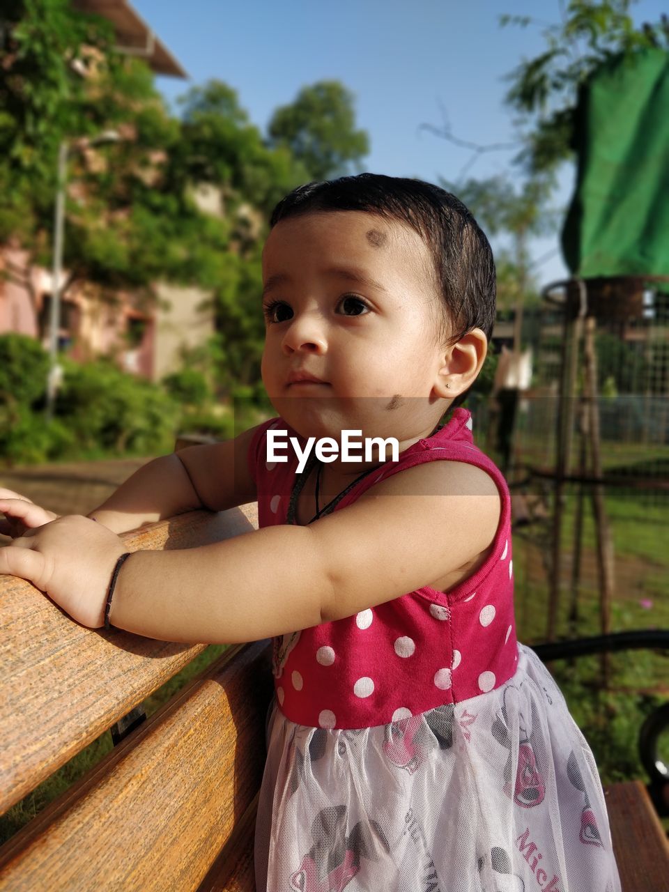 Close Up Of Cute Baby Girl Looking Away On Bench In On Eyeem