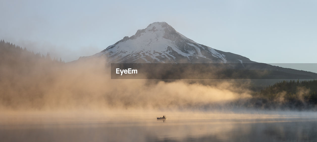 Panoramic view of boat in lake by snowcapped mountain against sky