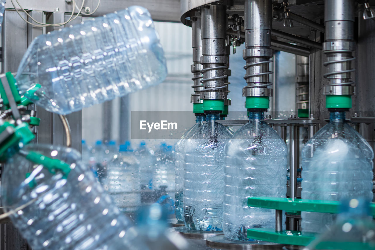 Five-liter plastic bottles are filled with water in a filling machine