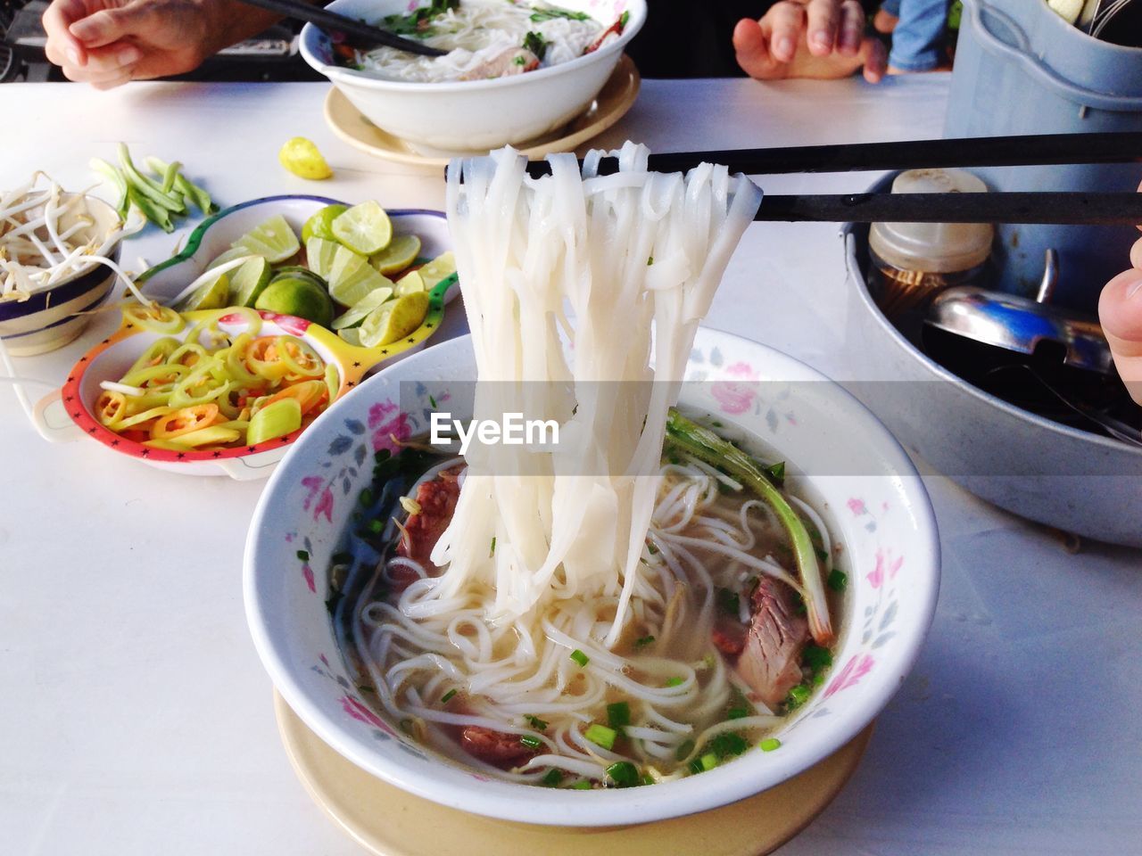 Chopsticks holding noodles in bowl on table