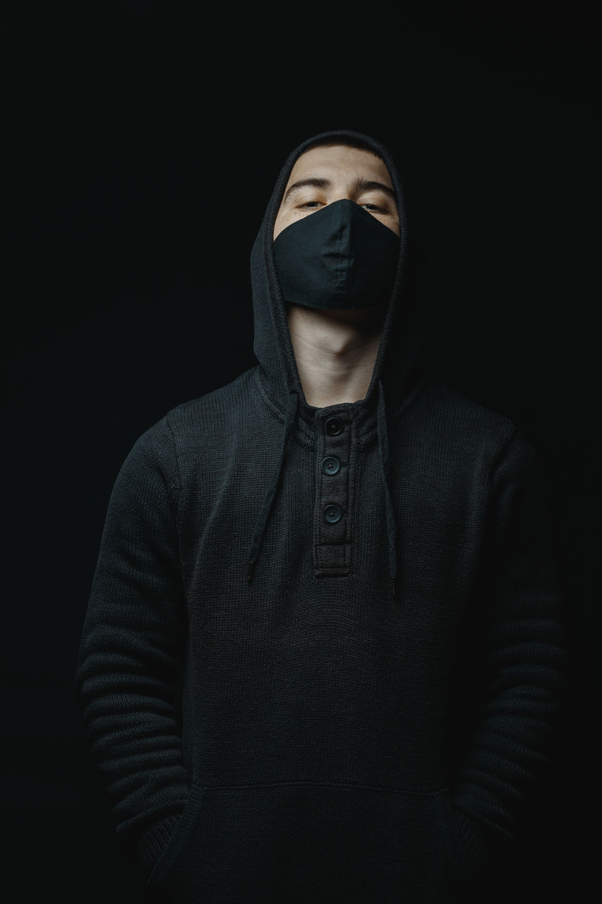 Portrait of man wearing mask against black background