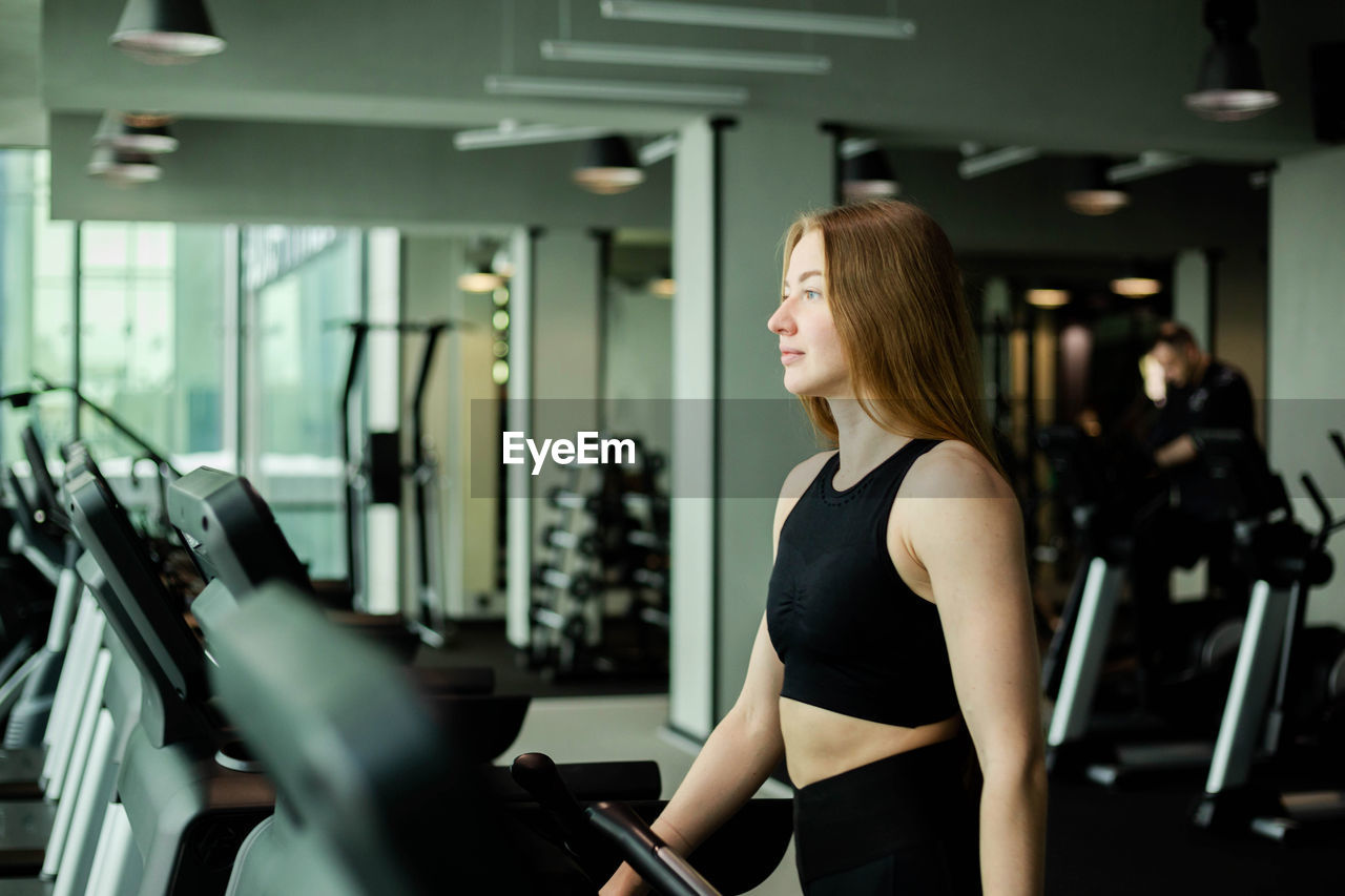 Happy athletic woman jogging on treadmills in a gym.