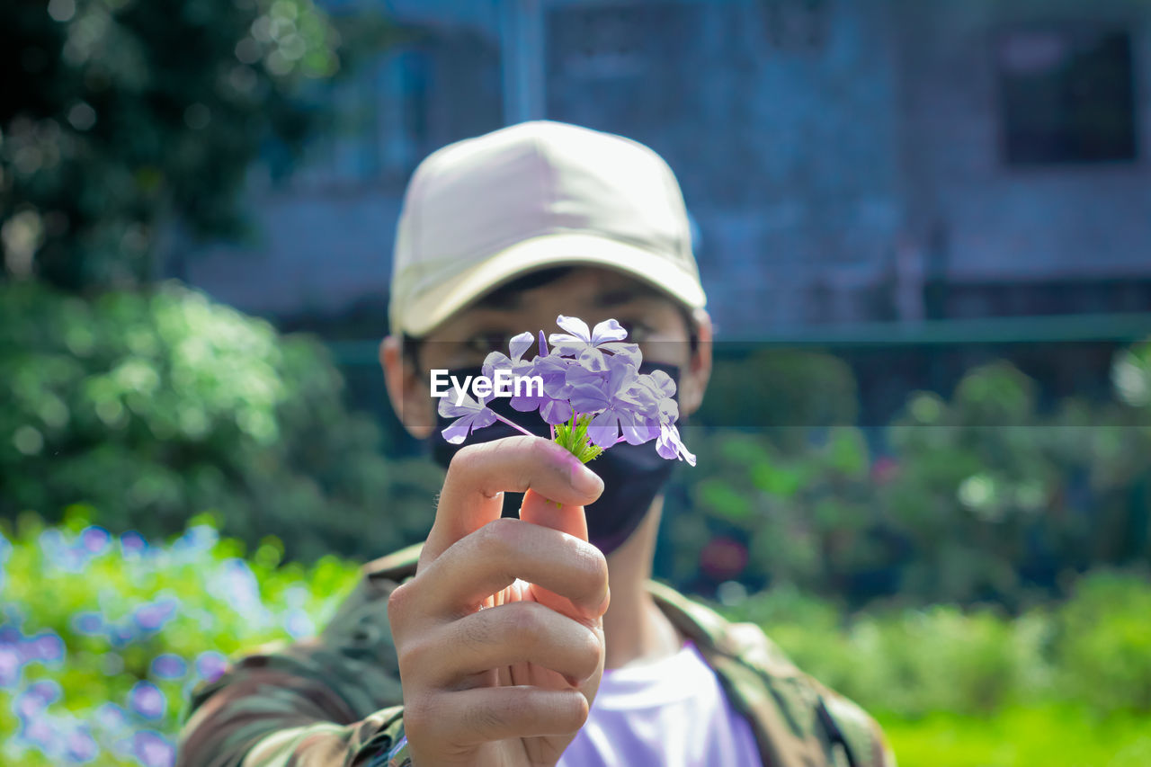 flower, flowering plant, plant, one person, spring, nature, portrait, headshot, holding, day, focus on foreground, outdoors, adult, childhood, freshness, fragility, child, women, beauty in nature, close-up, lifestyles, hat, clothing, leisure activity, fashion accessory, men, person