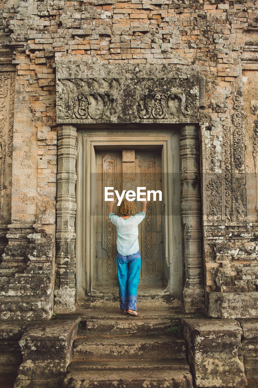 Rear view of woman standing at entrance of old temple