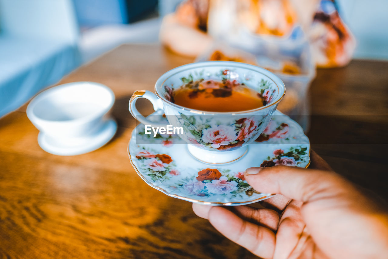 Cropped hand holding tea cup at home