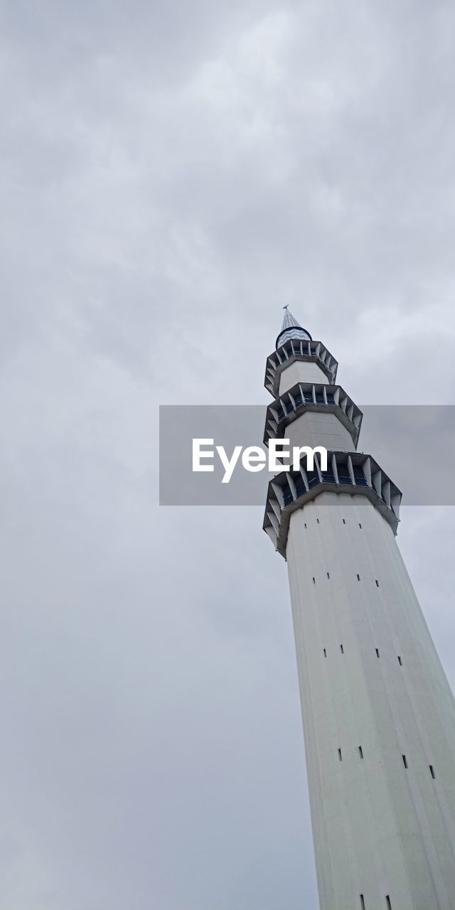 Low angle view of lighthouse by building against sky