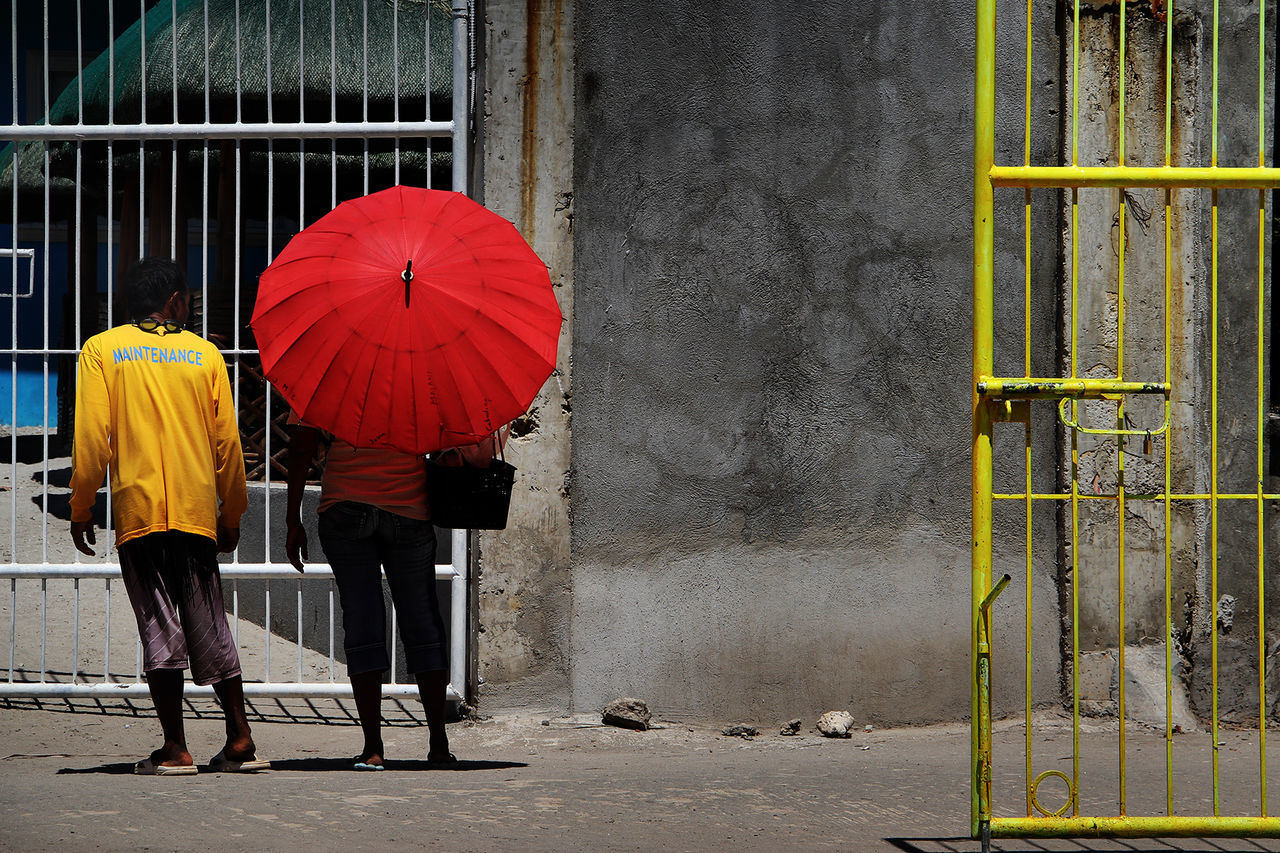REAR VIEW OF PEOPLE WALKING WITH UMBRELLA