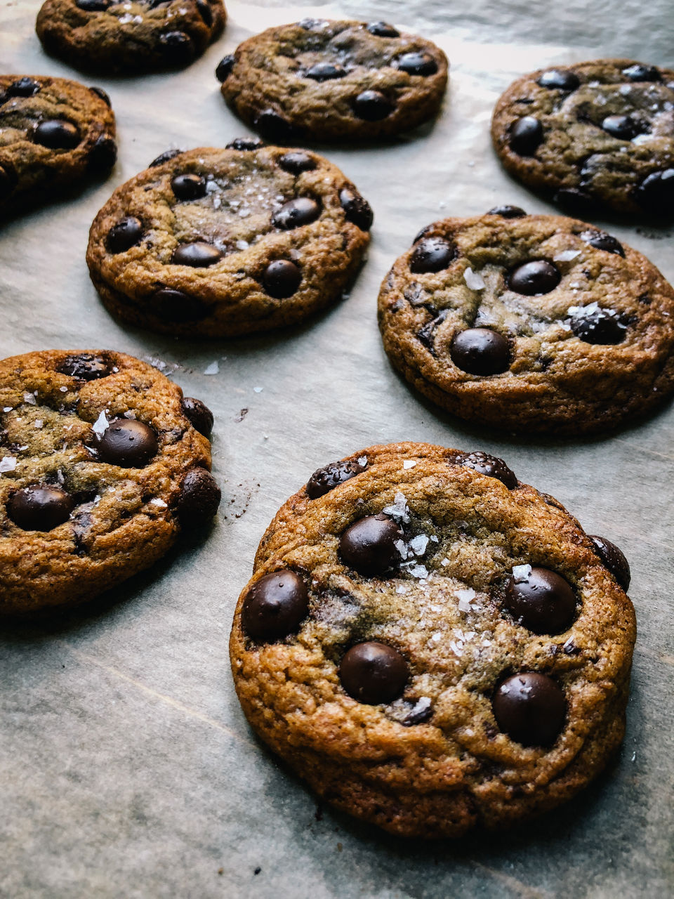 Fresh out-of-the-oven homemade chocolate chip cookies with fleur de sel on parchment paper