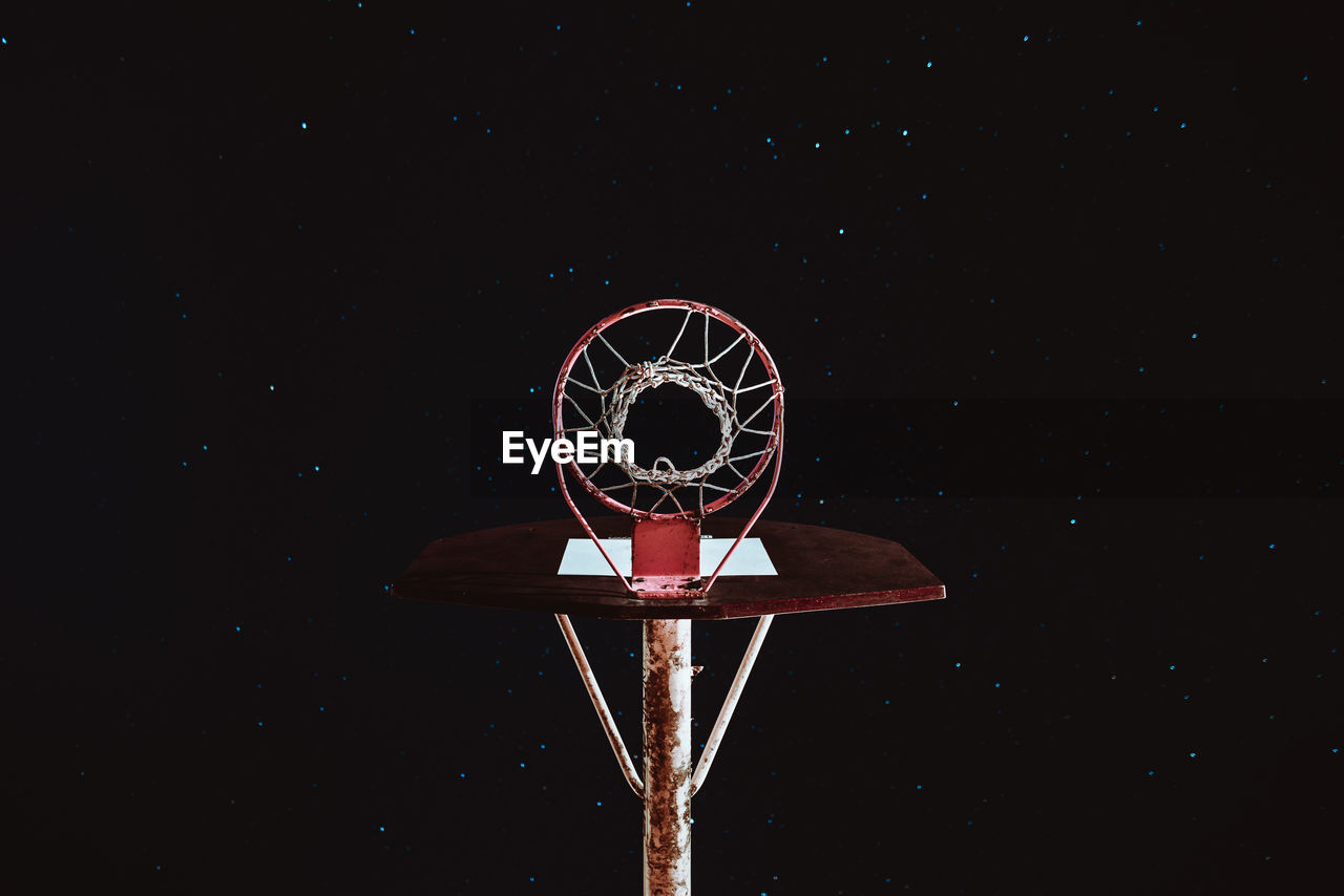 Basketball hoop against sky at night