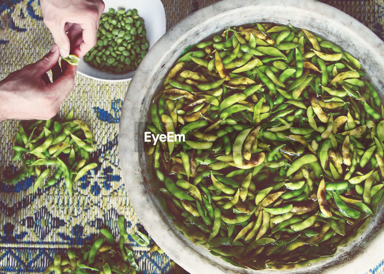 Cropped image of person shelling broad beans