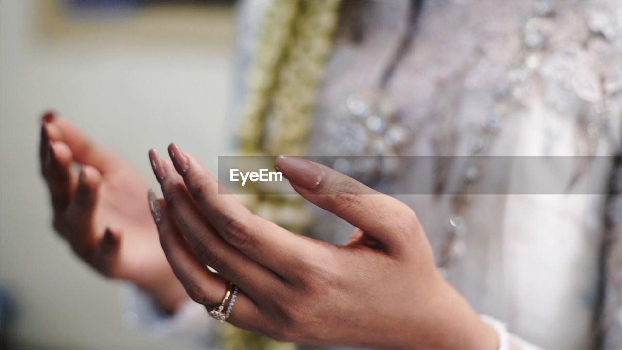 Midsection of woman gesturing while praying