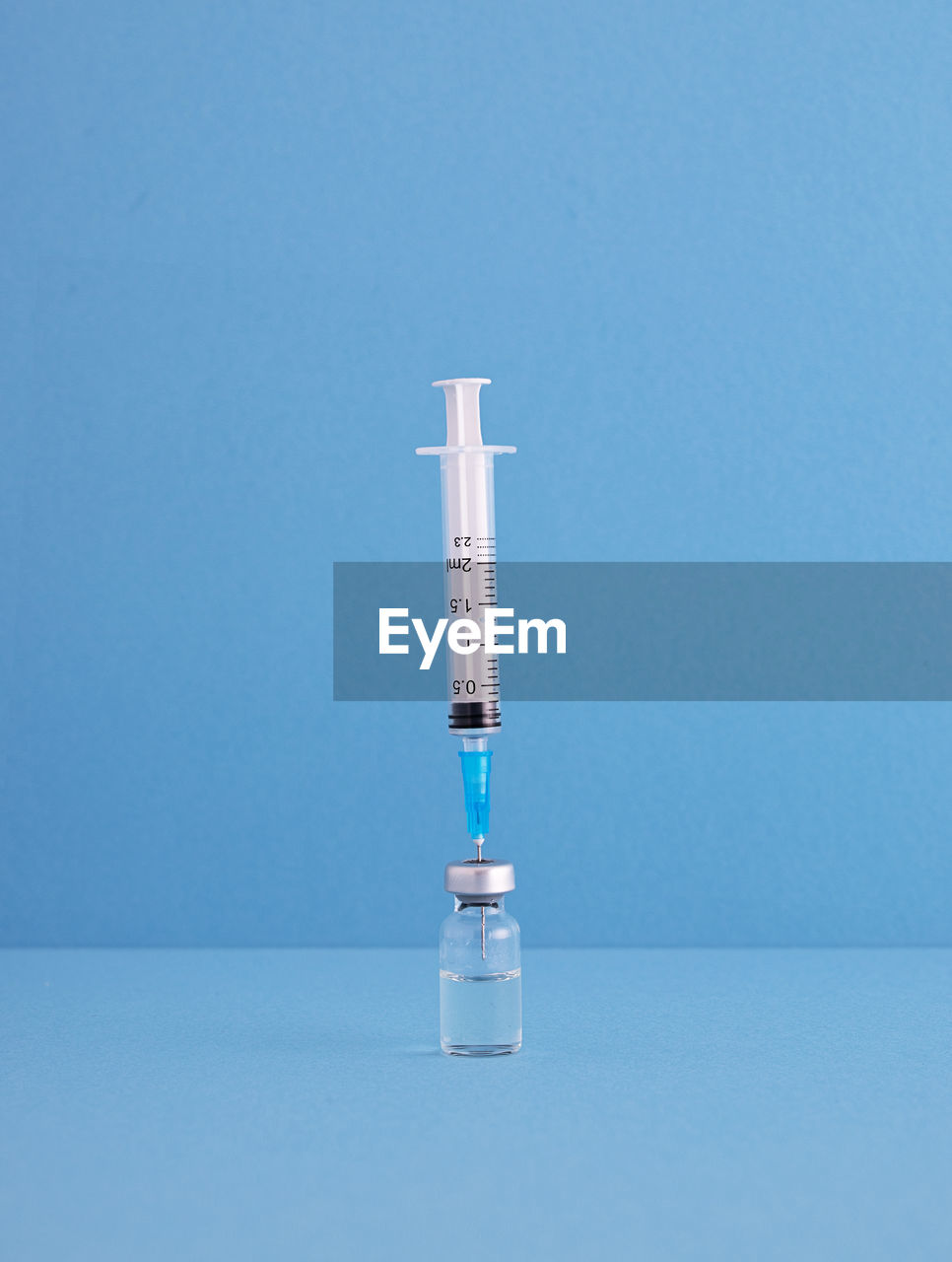 Close-up of syringe with vial on blue background