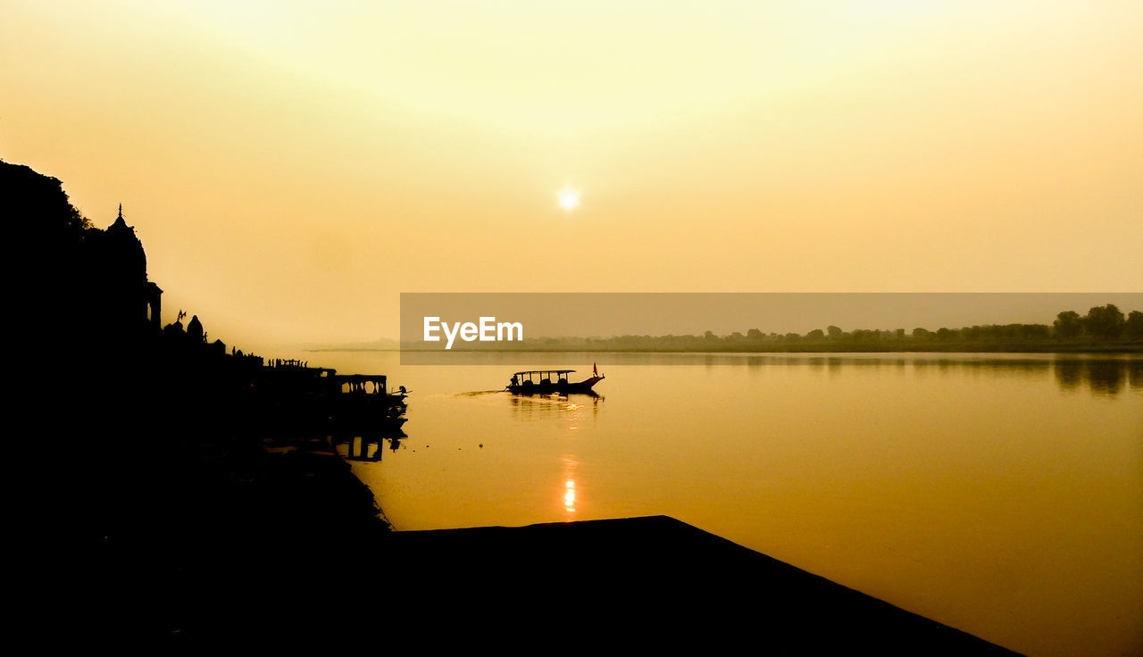 Silhouette temple by narmada river at sunset