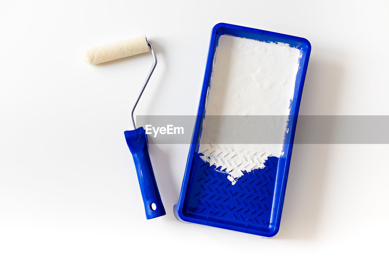 Paint roller and tray with white paint for interior renovation and decoration