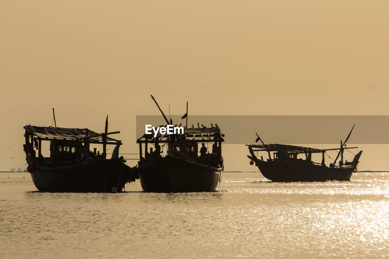 Three fishing boats in silhouette