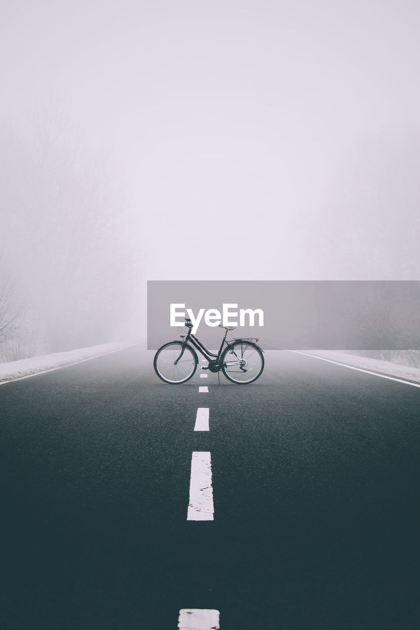 Bicycle parked on road during foggy weather