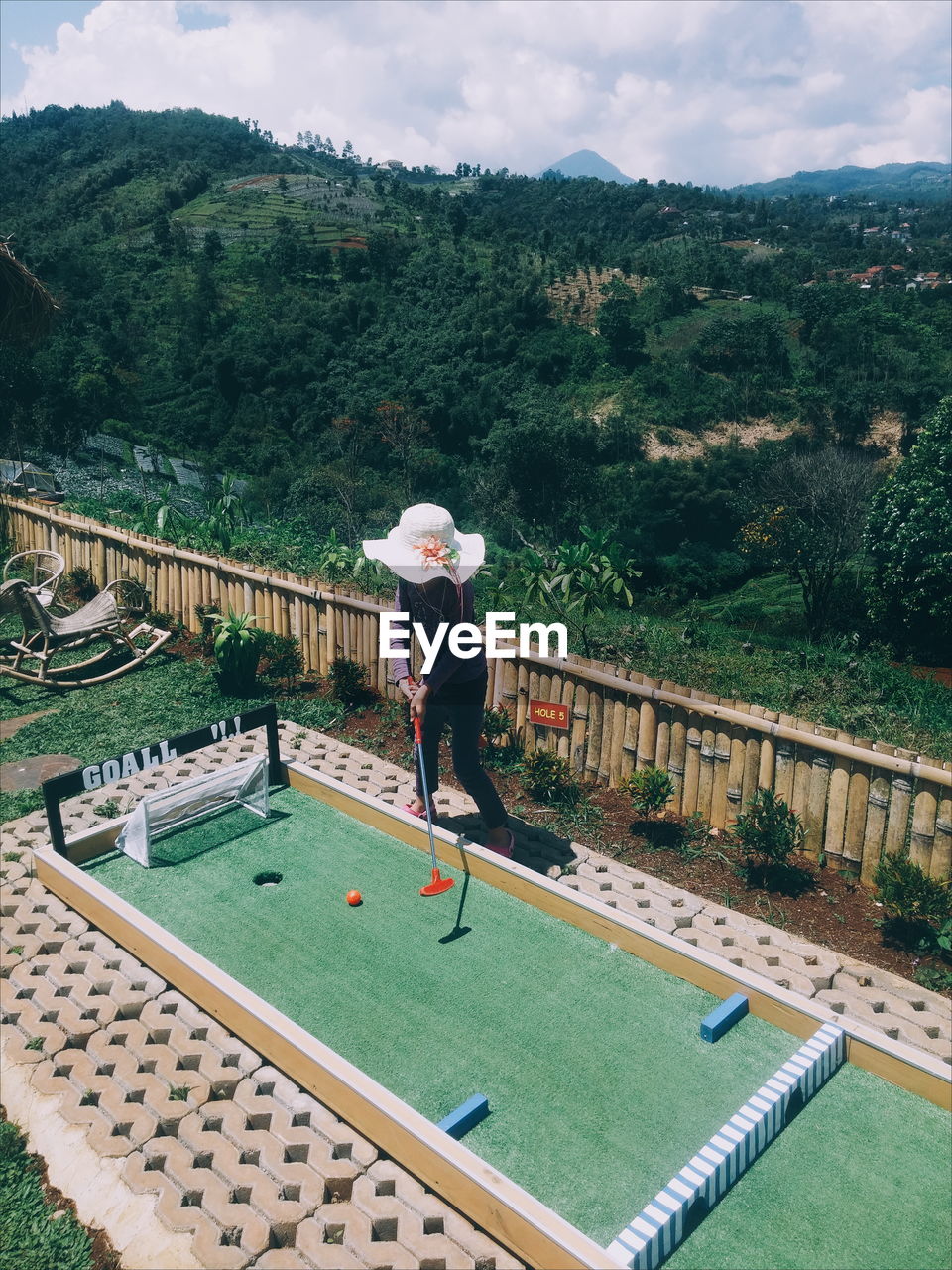 High angle view of girl playing miniature golf