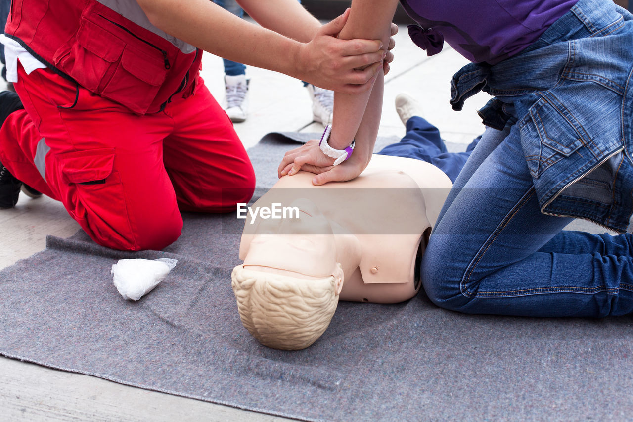 Instructor guiding woman to perform cpr on dummy
