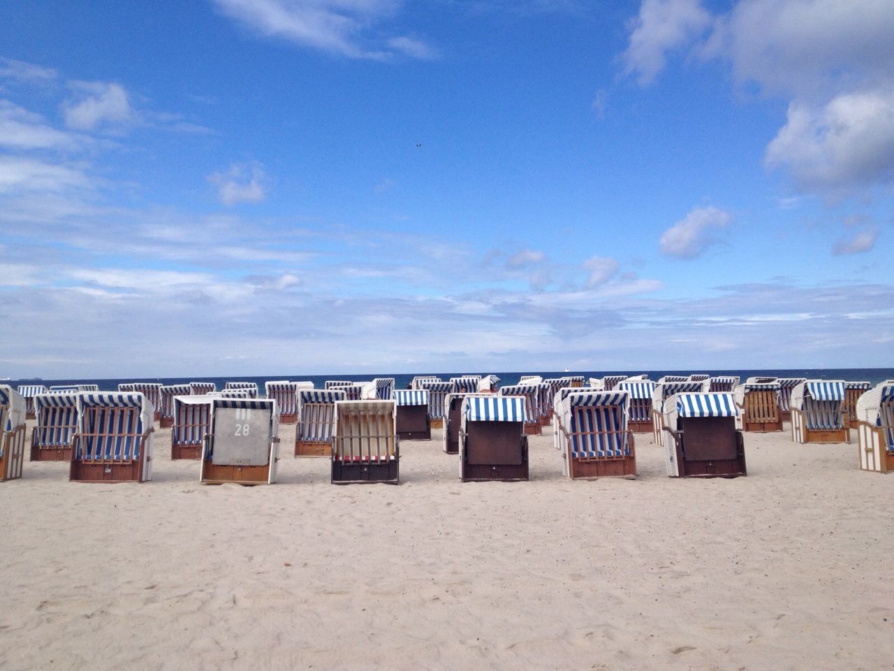Hooded beach chairs on sand against sky