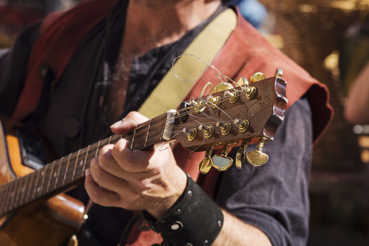MIDSECTION OF MAN PLAYING GUITAR AT CONCERT