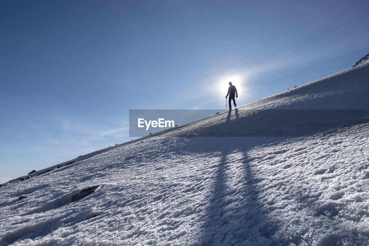 PERSON SKIING ON SNOWCAPPED MOUNTAIN AGAINST SKY