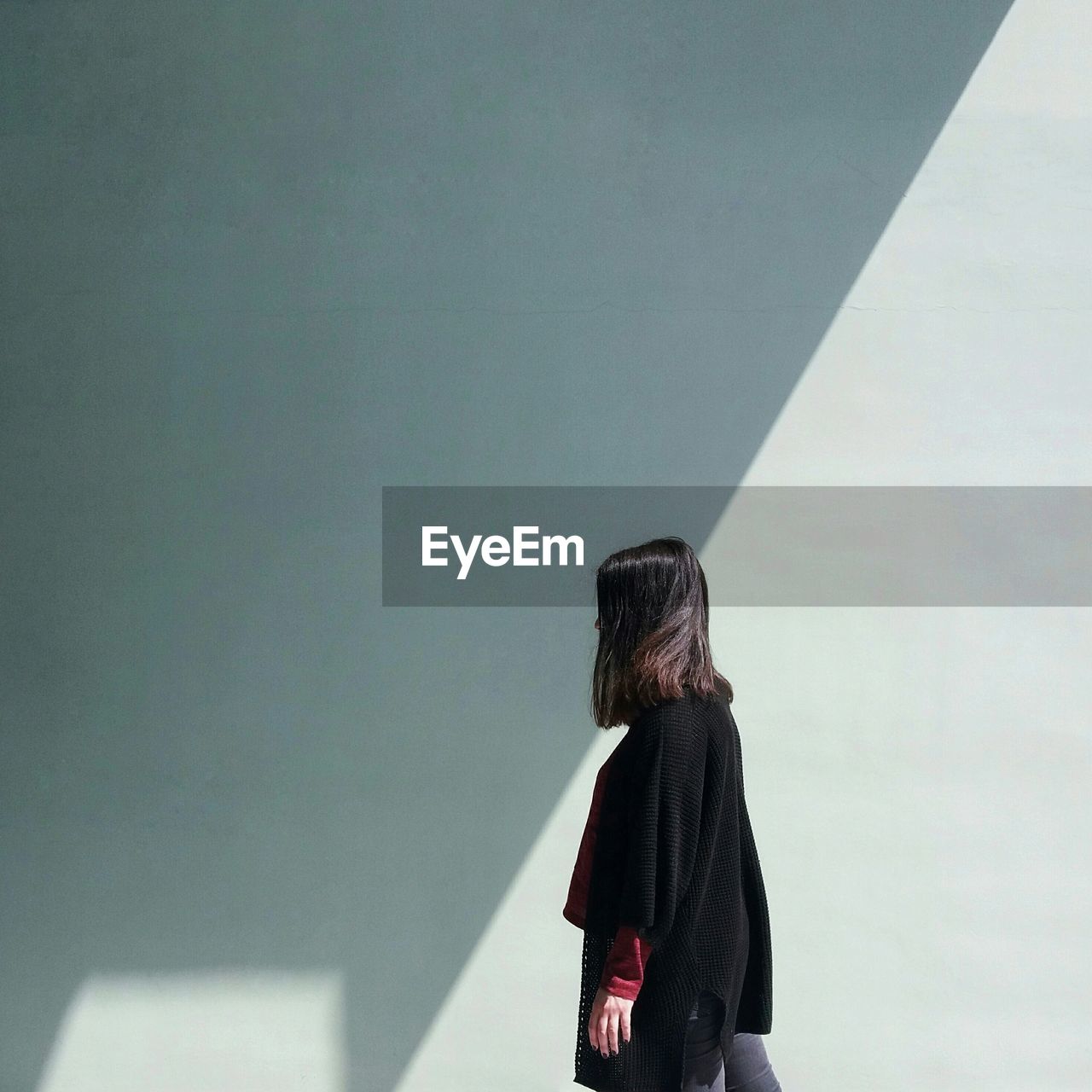 Side view of woman standing against wall