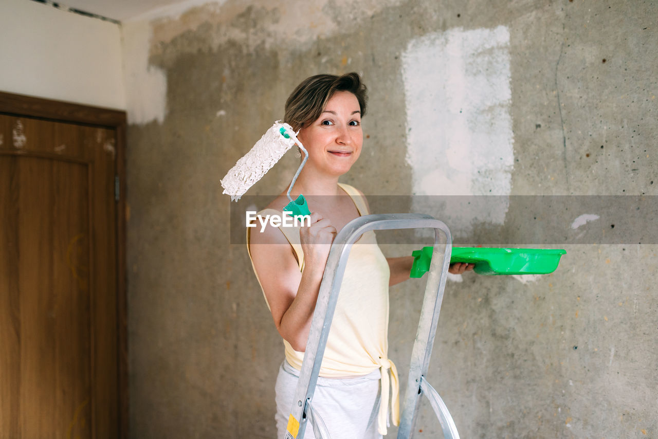 Portrait of smiling woman holding paint roller