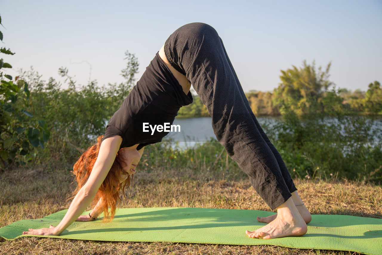 Side view of woman practicing yoga at lakeshore