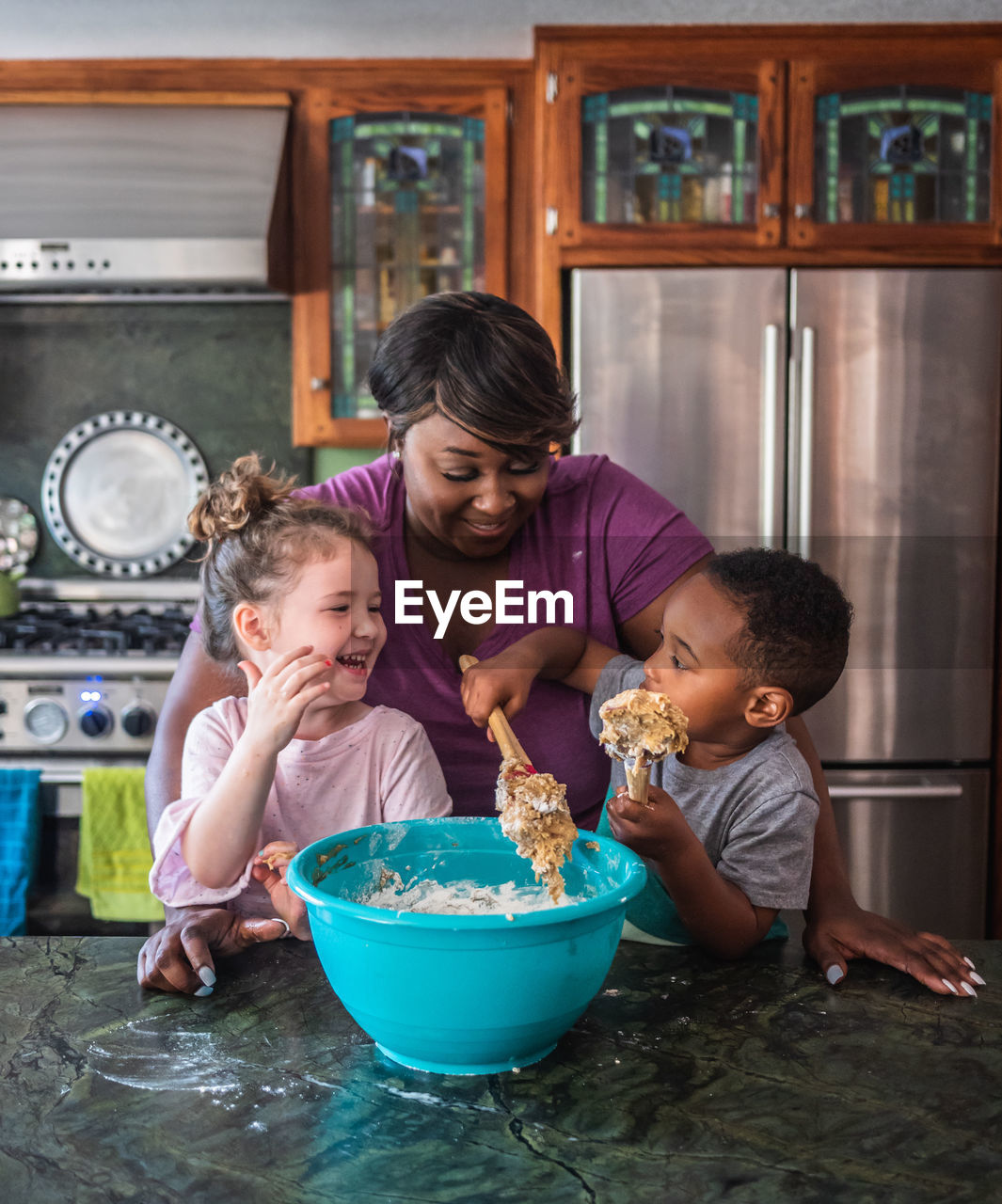 Mother smiling while kids make cookies together