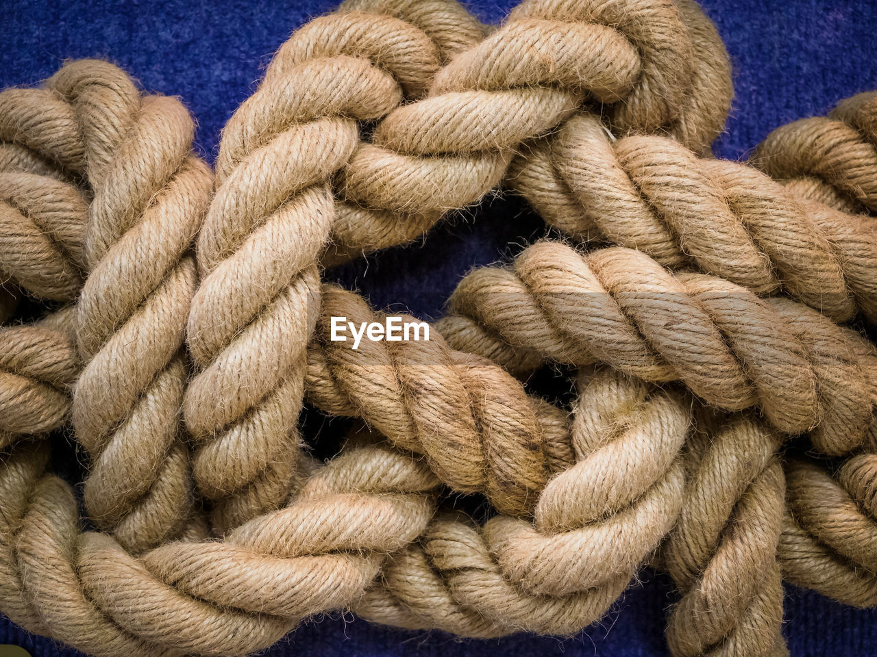 CLOSE-UP OF ROPE TIED UP ON BLUE