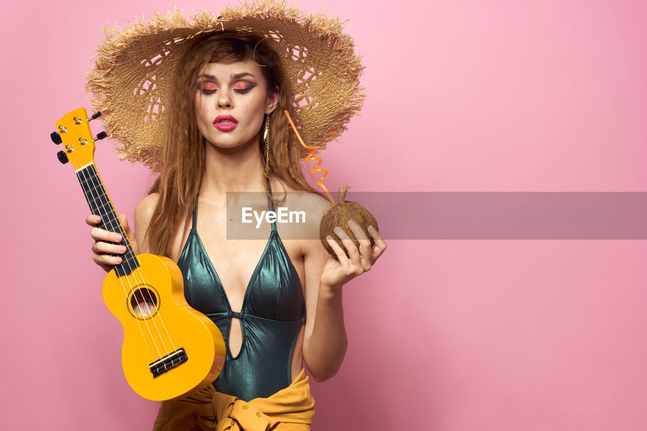 studio shot, music, one person, young adult, adult, arts culture and entertainment, portrait, guitar, colored background, women, musical instrument, curly hair, hairstyle, fashion, string instrument, musician, yellow, clothing, indoors, rock music, person, pink, long hair, looking at camera, individuality, photo shoot, copy space, human face, cool attitude, cartoon, multi colored, front view, waist up, performance, lifestyles, holding, female, electric guitar