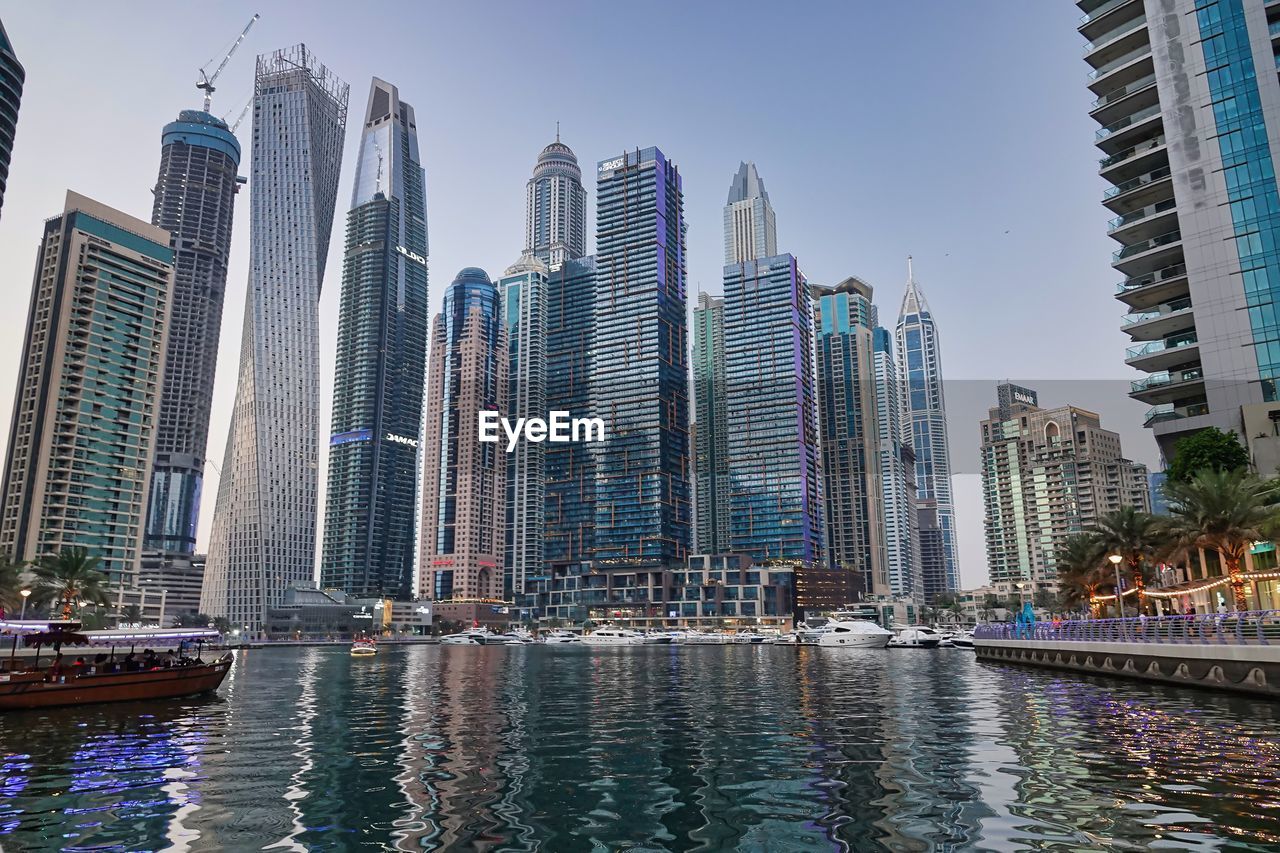 Boats in river in city against sky