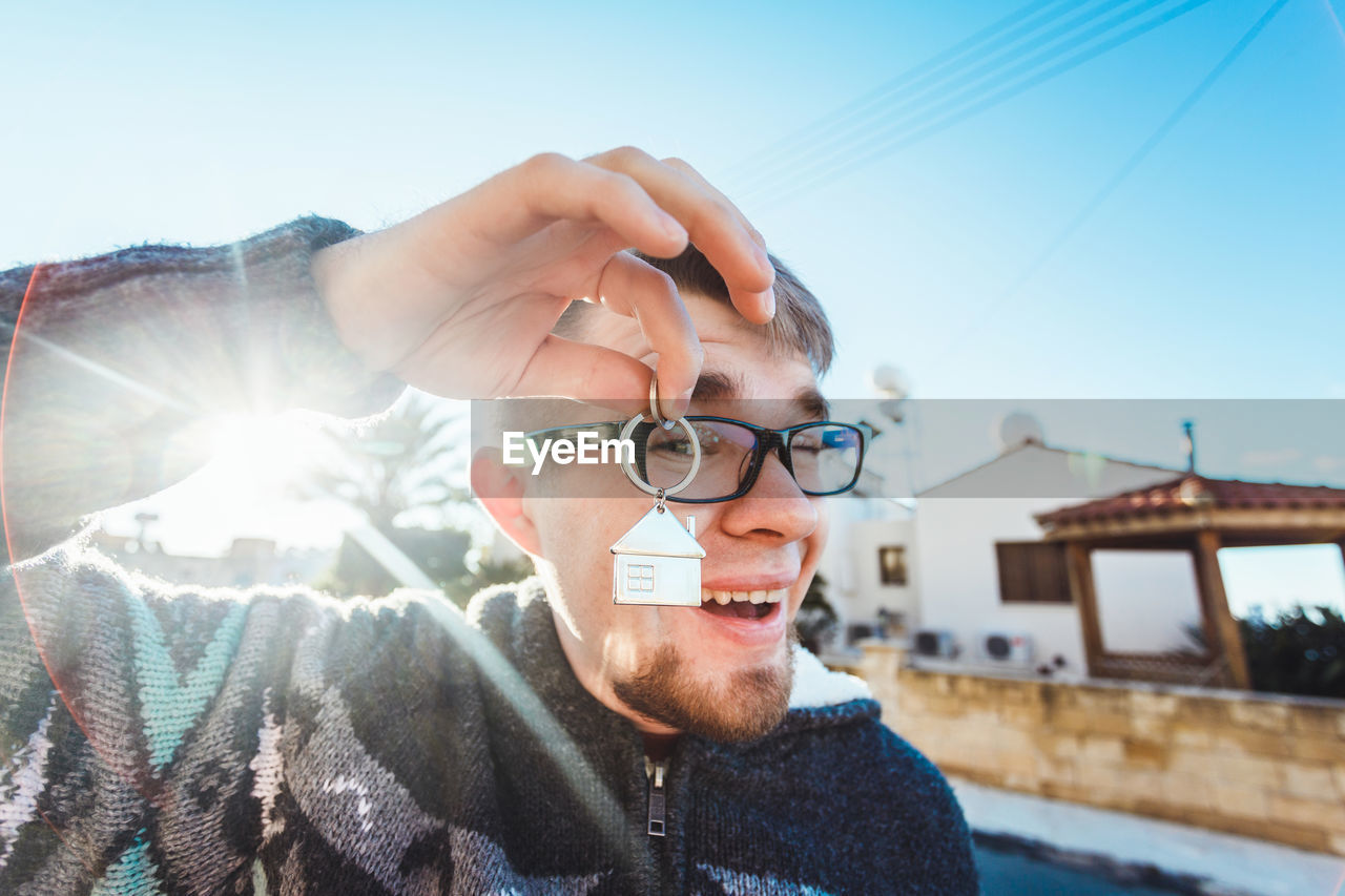 PORTRAIT OF YOUNG MAN WITH EYEGLASSES ON CAMERA AGAINST SKY