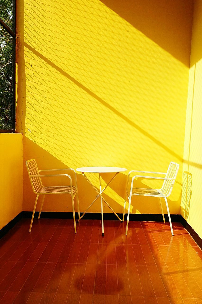 Table and chairs against yellow wall