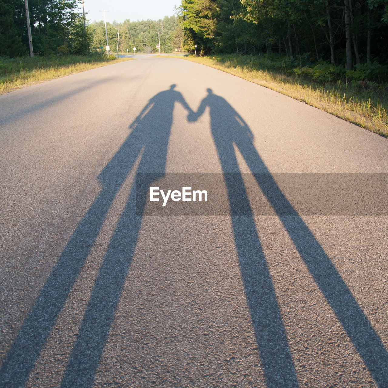 Shadow of couple holding hands on road