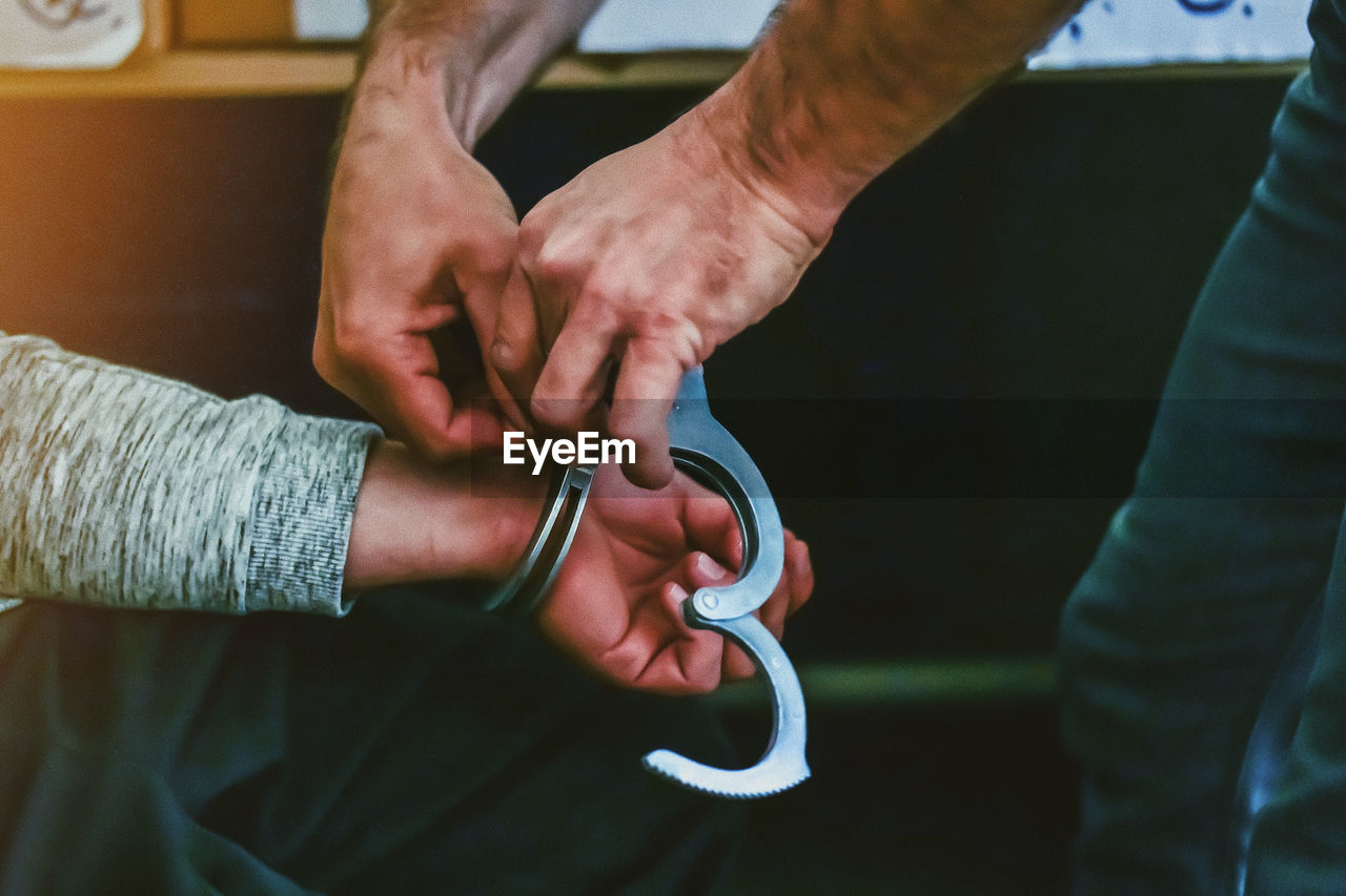Close-up of man holding hand with handcuffs